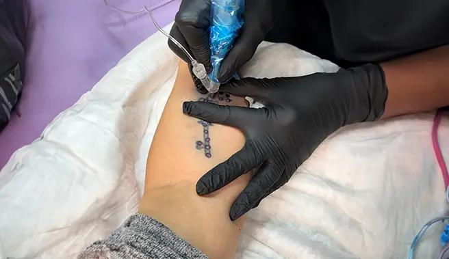 A person with black gloves on getting a tattoo.