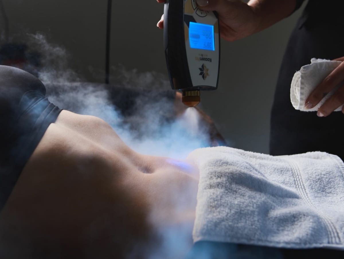 A person holding a cell phone in front of a smoke filled room.