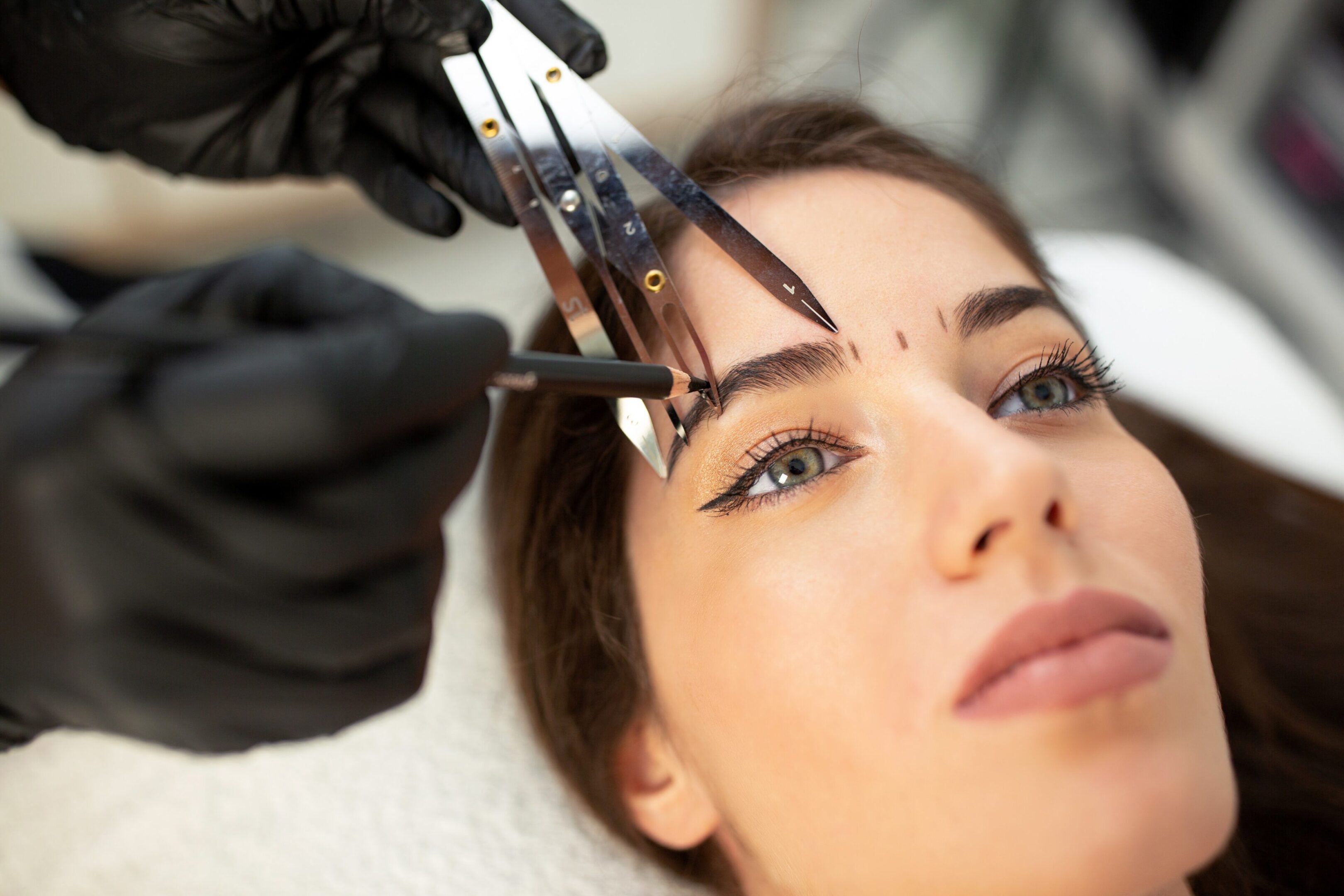 A woman getting her eyebrows threaded by an esthetician.