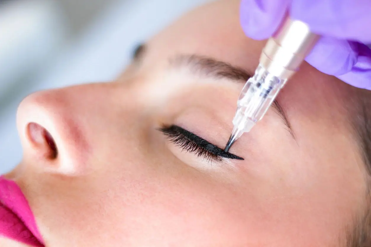 A woman is getting her eyebrows tattooed