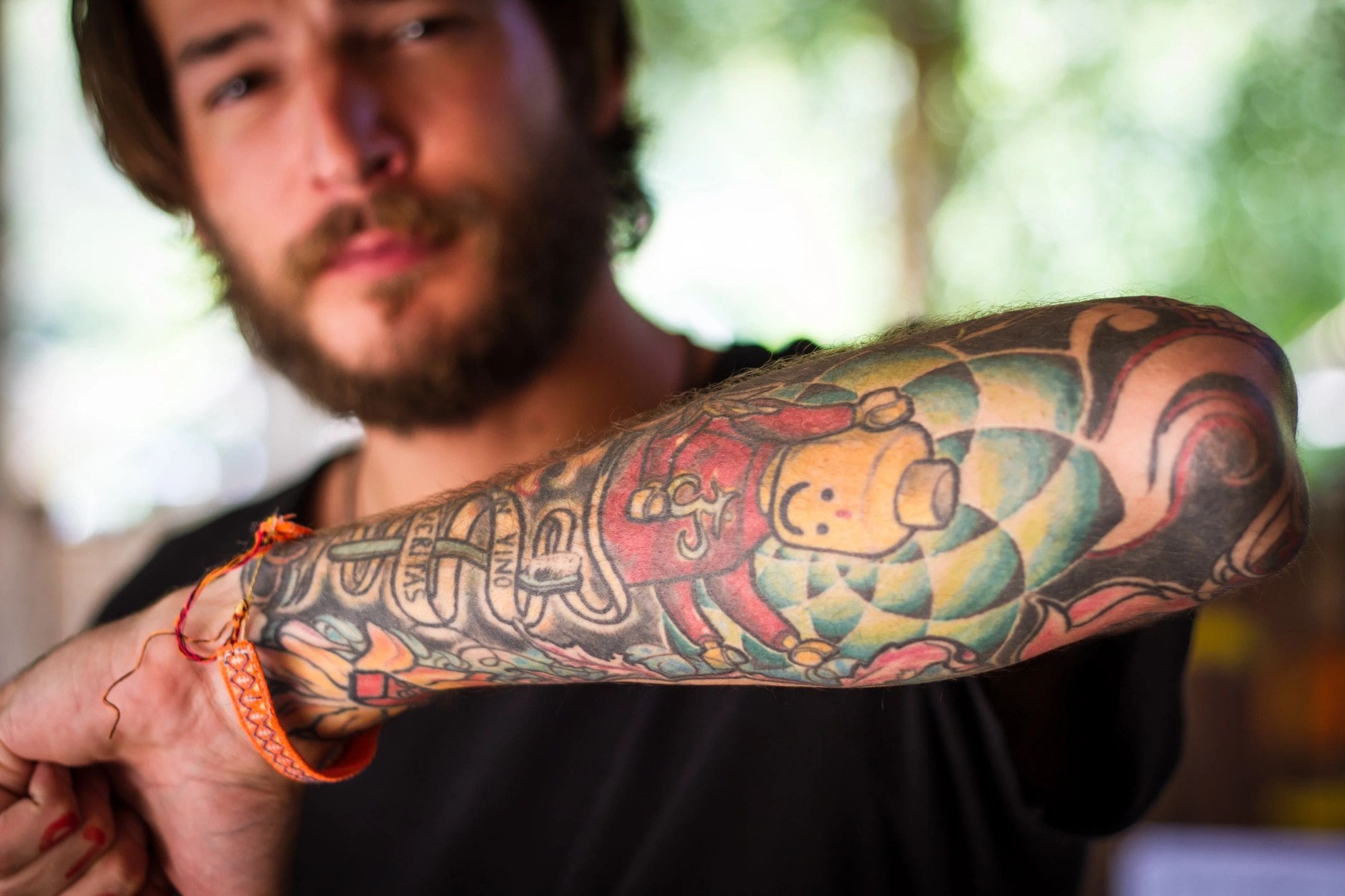 A man with a beard and tattoos on his arm.