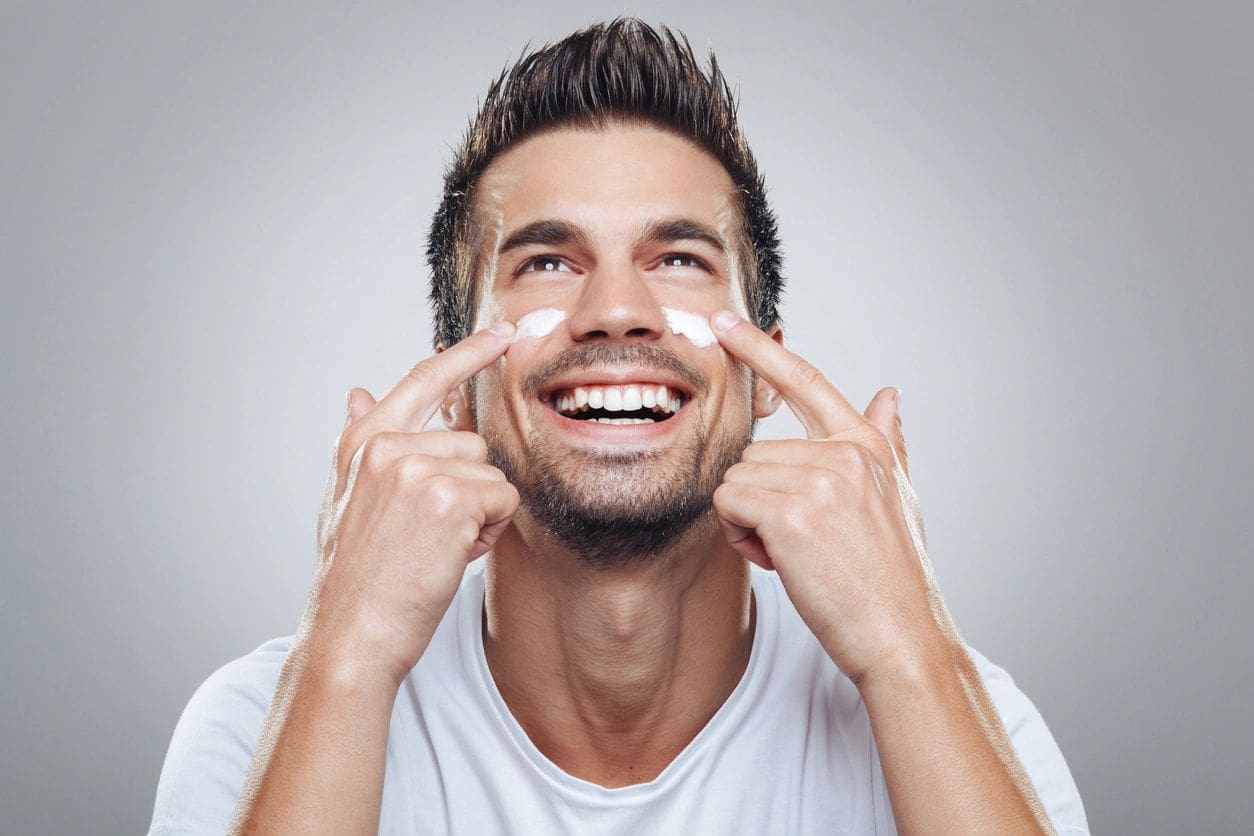 A man putting lotion on his face.