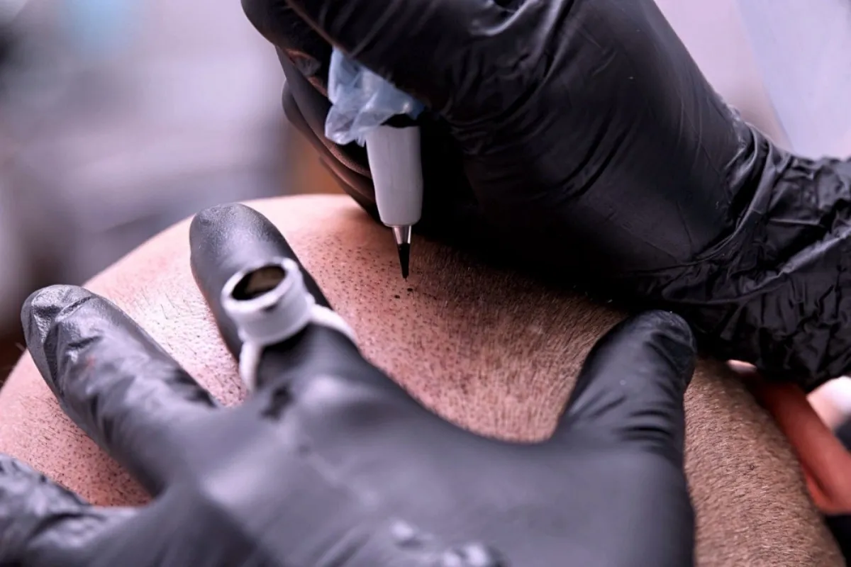 A person is getting their hands tattooed on the back of his leg.