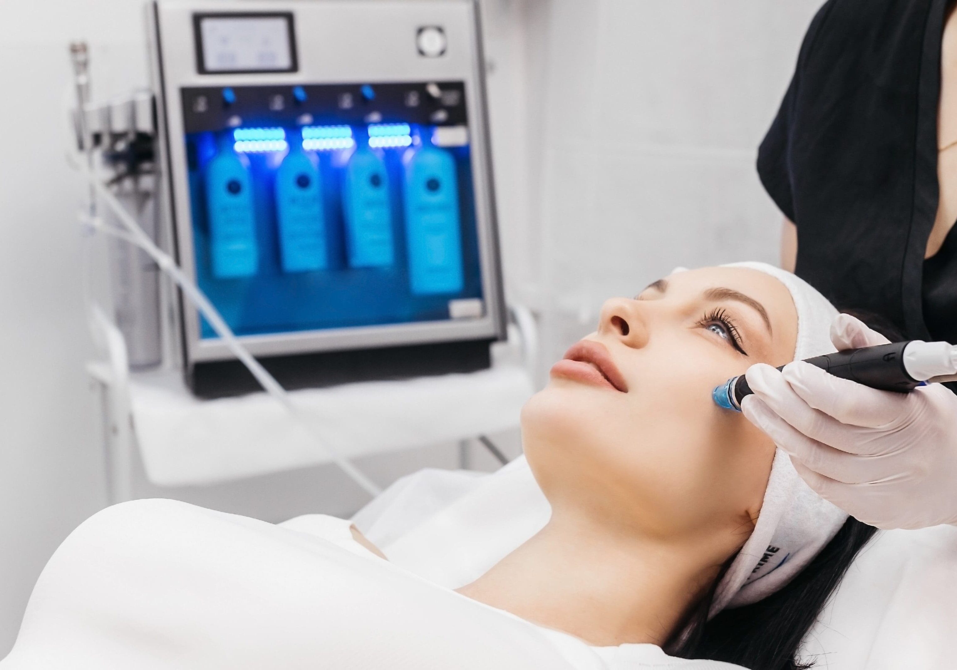 A woman getting her face cleaned by an esthetician.