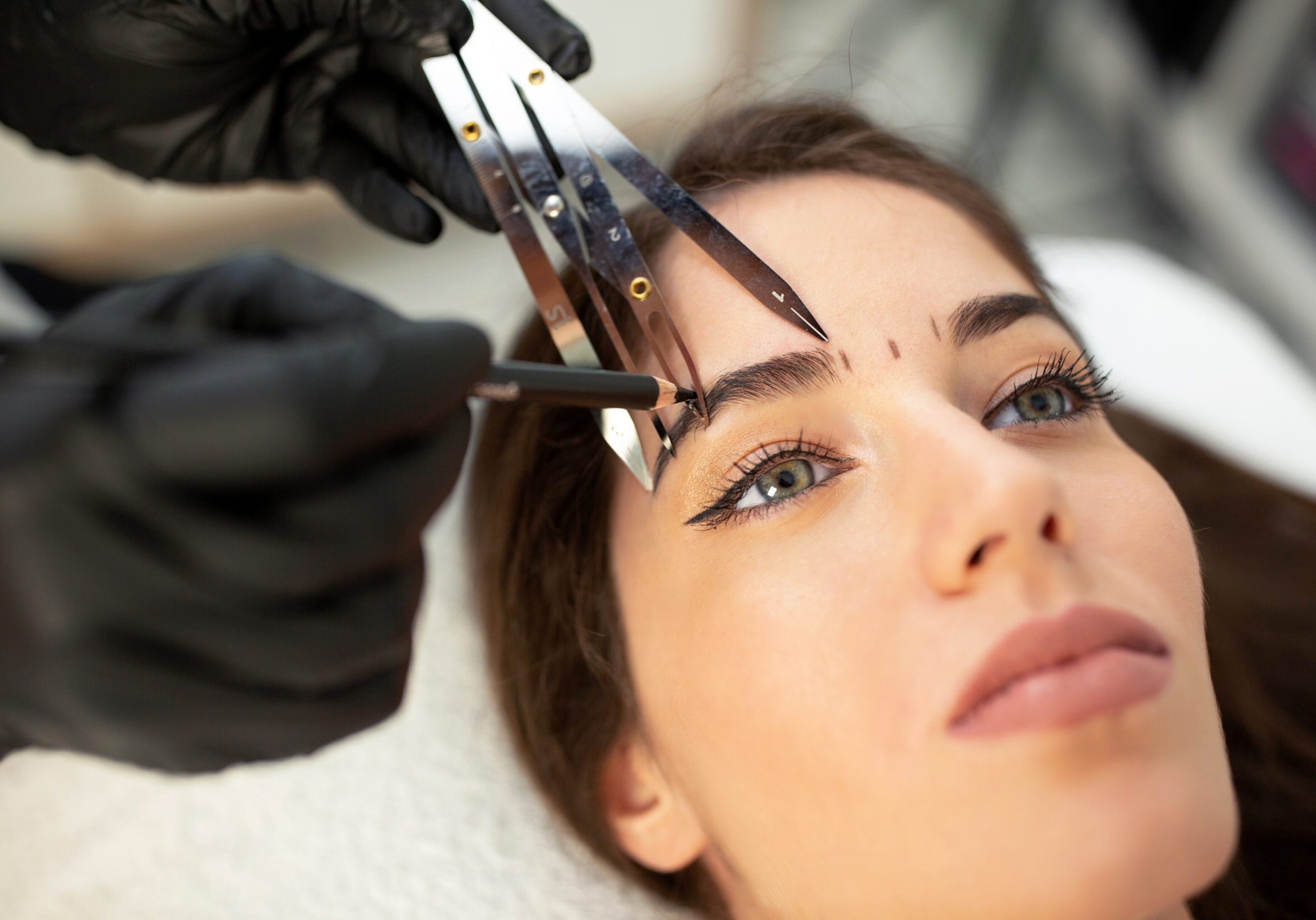 A woman getting her eyebrows threaded by an esthetician.