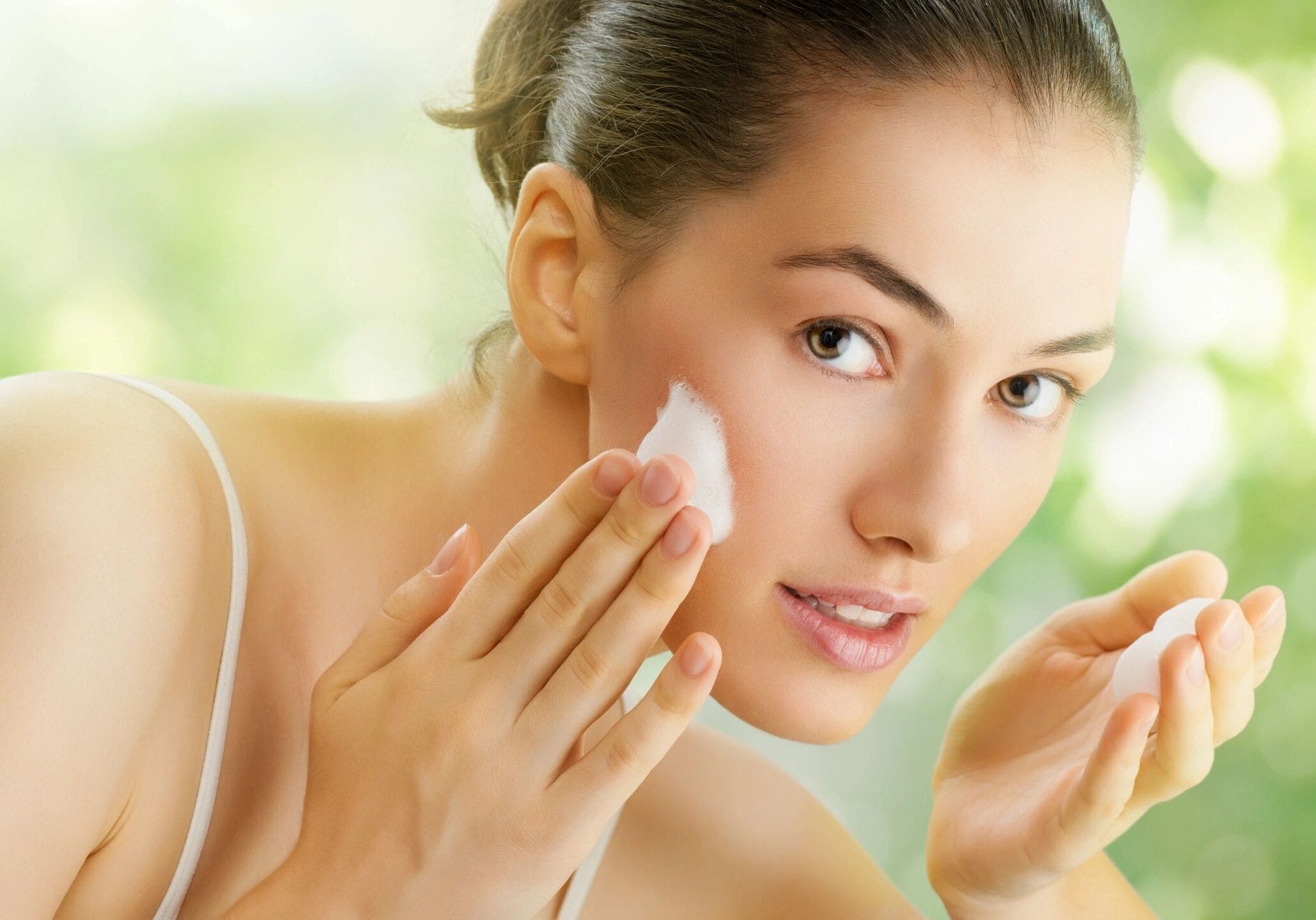 A woman is putting on makeup in the mirror