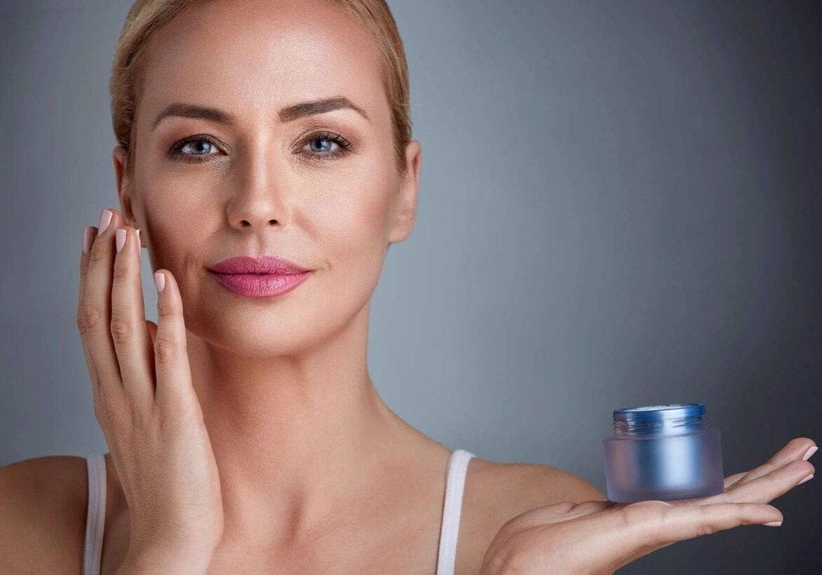 A woman holding a jar of cream in her hand.