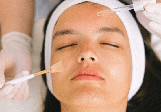 A woman getting her face waxed by two hands.