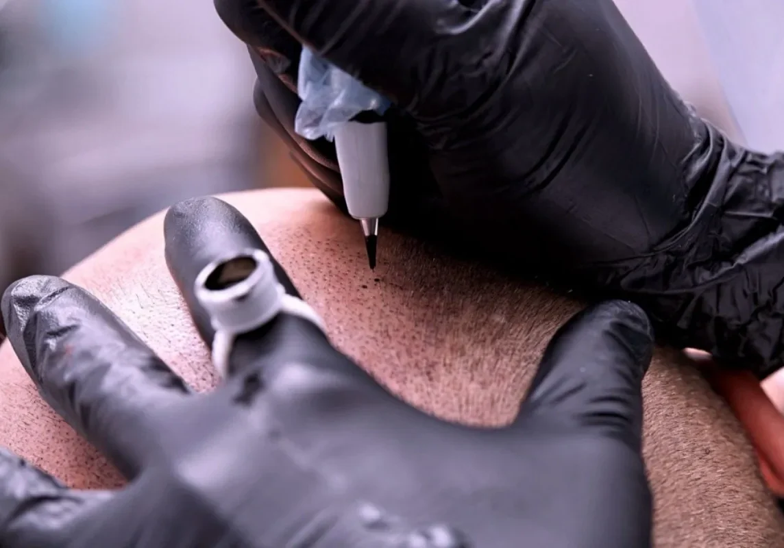 A person is getting their hands tattooed on the back of his leg.